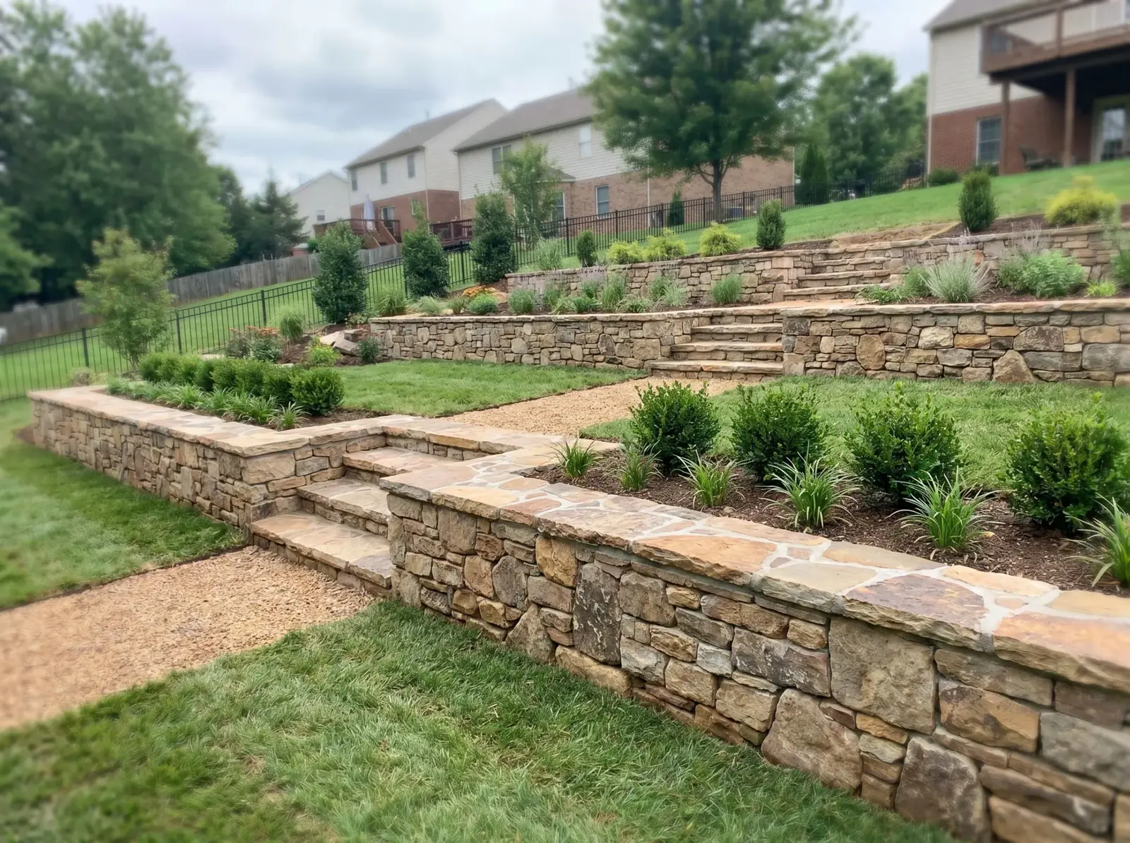 Terraced natural stone retaining walls with stone steps on a sloped East Tennessee yard